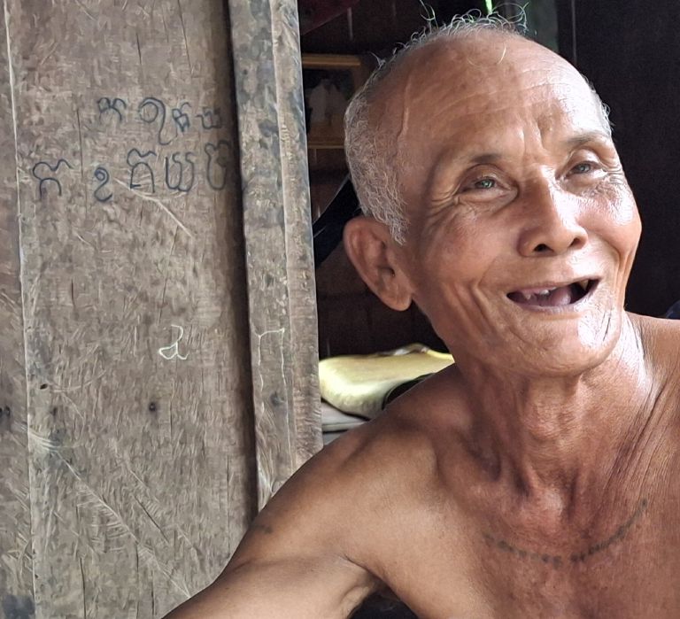 A Kampot durian farmer laughing outside his home