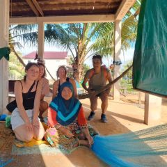 Visitors learning to mend fishing nets in a Cham village